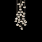 A tall cluster of clear glass heads on this Clérachic pendant hangs on thin cords against a black backdrop.