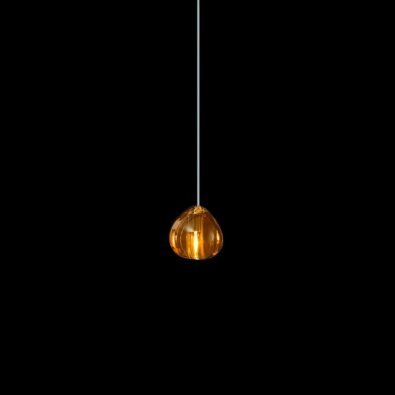 A single amber glass head on this Clérachic pendant hangs on a pale cord against a black backdrop.