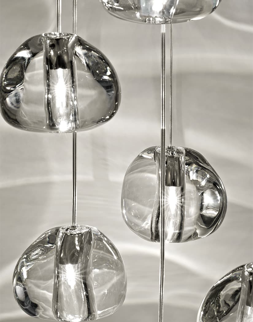 Close view of clear, irregular glass heads on this Clérachic pendant, with patterns of light across the wall behind them.