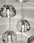 Close view of clear, irregular glass heads on this Clérachic pendant, with patterns of light across the wall behind them.