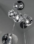 Looking up at a black ceiling canopy, this Clérachic pendant's clear glass heads cluster close together before the wires drop away.