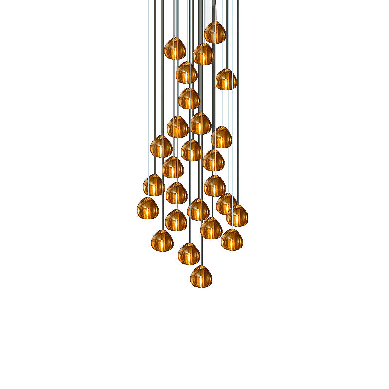 A full cluster of amber glass heads on this Clérachic pendant hangs in a tapering mass from cords on a plain white background.