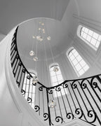 A black-and-white view looking up into a round stairwell with arched windows, with this Clérachic pendant hanging in its centre.