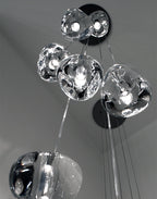 From below, a tight group of clear glass heads on this Clérachic pendant rises towards a round black canopy.