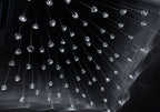 Hundreds of small clear glass heads on this Clérachic pendant hang from fine wires in the dark, with streaks of light below them.