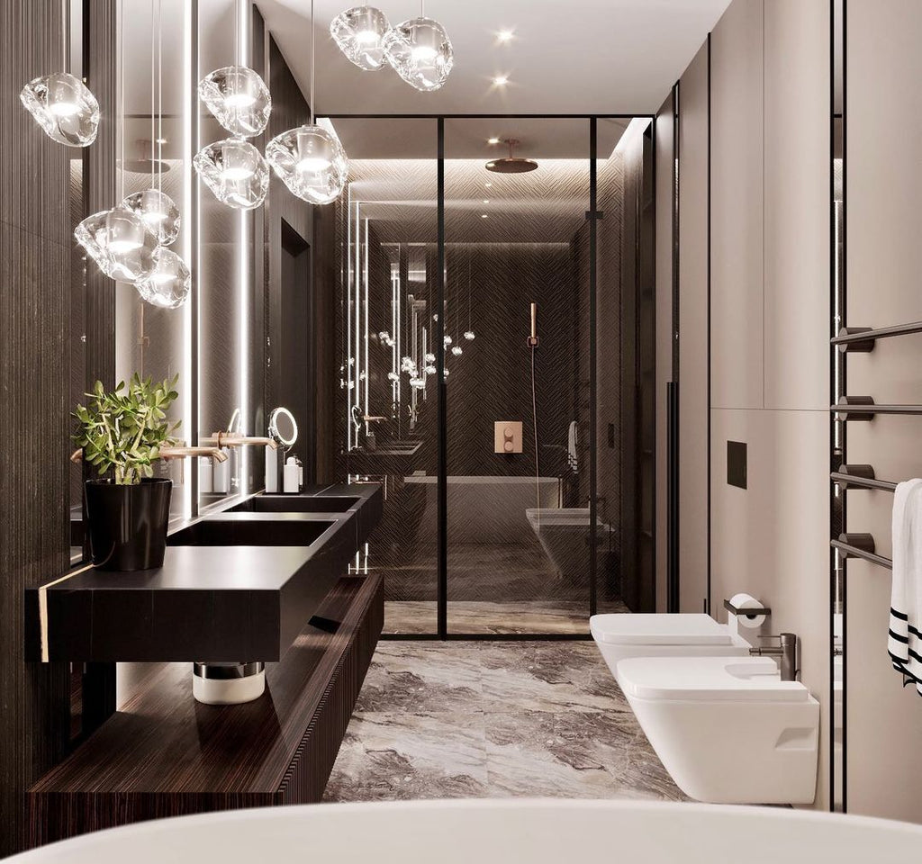A dark bathroom with a double basin and a glazed shower, with the clear glass heads of this Clérachic pendant hanging at upper left.
