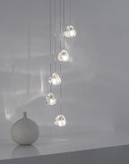 Five clear glass heads of this Clérachic pendant hang in a line over a grey sill, with a round white vase below.