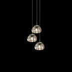Three clear glass heads of this Clérachic pendant hang on pale cords against a pure black background.