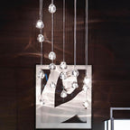 Clear glass heads of this Clérachic pendant hang against a dark wood wall, in front of a large framed black-and-white picture.
