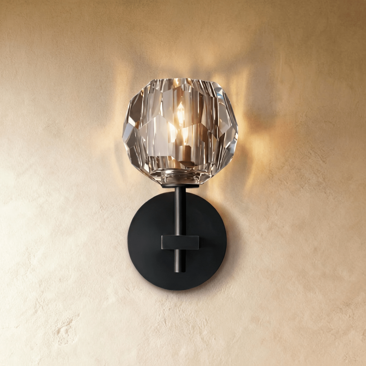 Clérachic short black wall sconce, a lit faceted crystal shade above a round black wall plate on textured plaster.