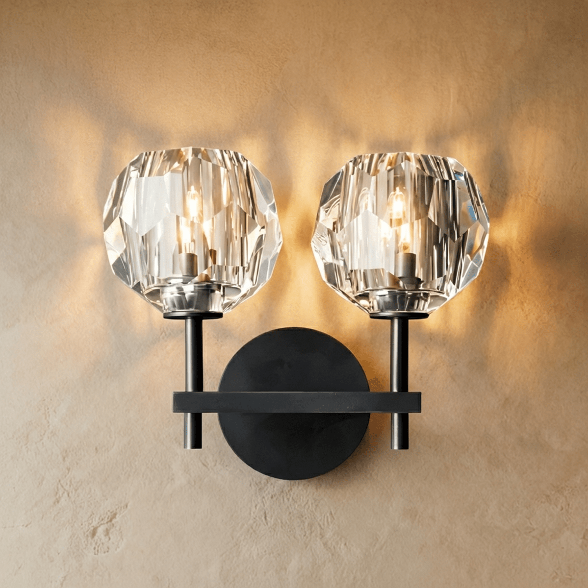 Clérachic two-head black wall sconce, twin faceted crystal shades lit warm on a crossbar and round plate.