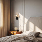 Clérachic black wall sconce with a crystal shade above a wooden bedside table, beside a striped headboard and linen curtain.
