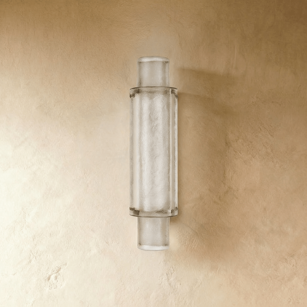 Clérachic slim vertical wall light of frosted textured crystal in a metal frame, unlit, on a warm limewashed wall.