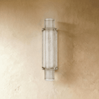 Clérachic slim vertical wall light of frosted textured crystal in a metal frame, unlit, on a warm limewashed wall.