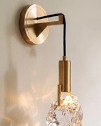 Clérachic crystal wall sconce, a faceted glass stone hanging from a brass rod fixed to a round wall plate.