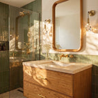 Two Clérachic crystal wall sconces flank a mirror in a green-tiled bathroom beside an open glass shower.