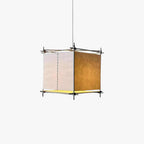 Cube paper lantern pendant from Clérachic with a slim dark metal frame and a glowing base, hung on a thin cord on white.