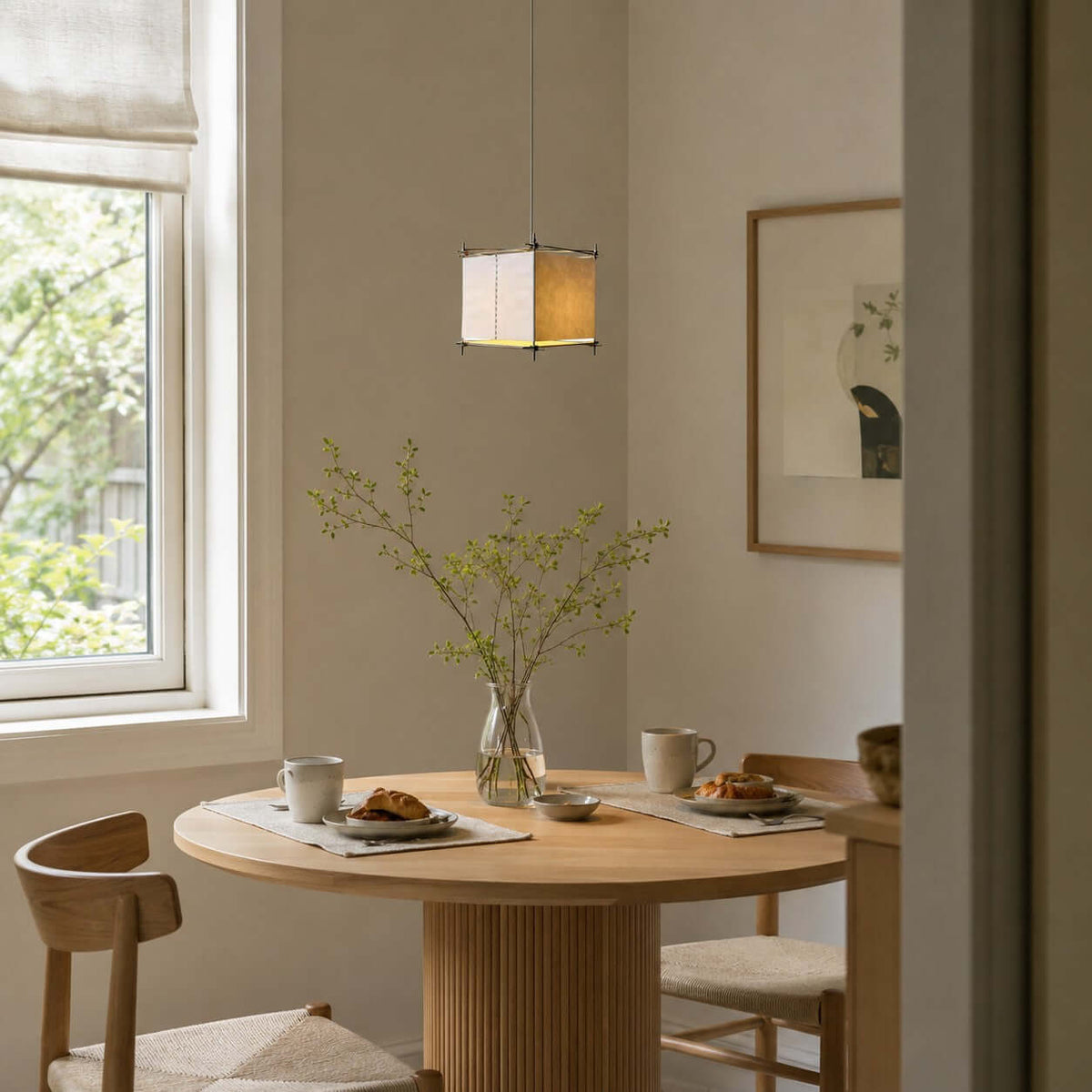 Clérachic paper pendant with a metal frame above a round table with breakfast pastries, near a sunny window.