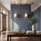 Pair of single-light Clérachic sconces on a blue panelled wall above a dark console table, with an olive branch in a vase.