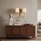 Two-light alabaster sconce from Clérachic above a walnut cabinet, with a marble bust and a small plant on top.