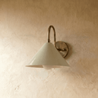 Clérachic cone-shade wall sconce in vintage brass, photographed on a plain plaster wall from a slightly closer angle.
