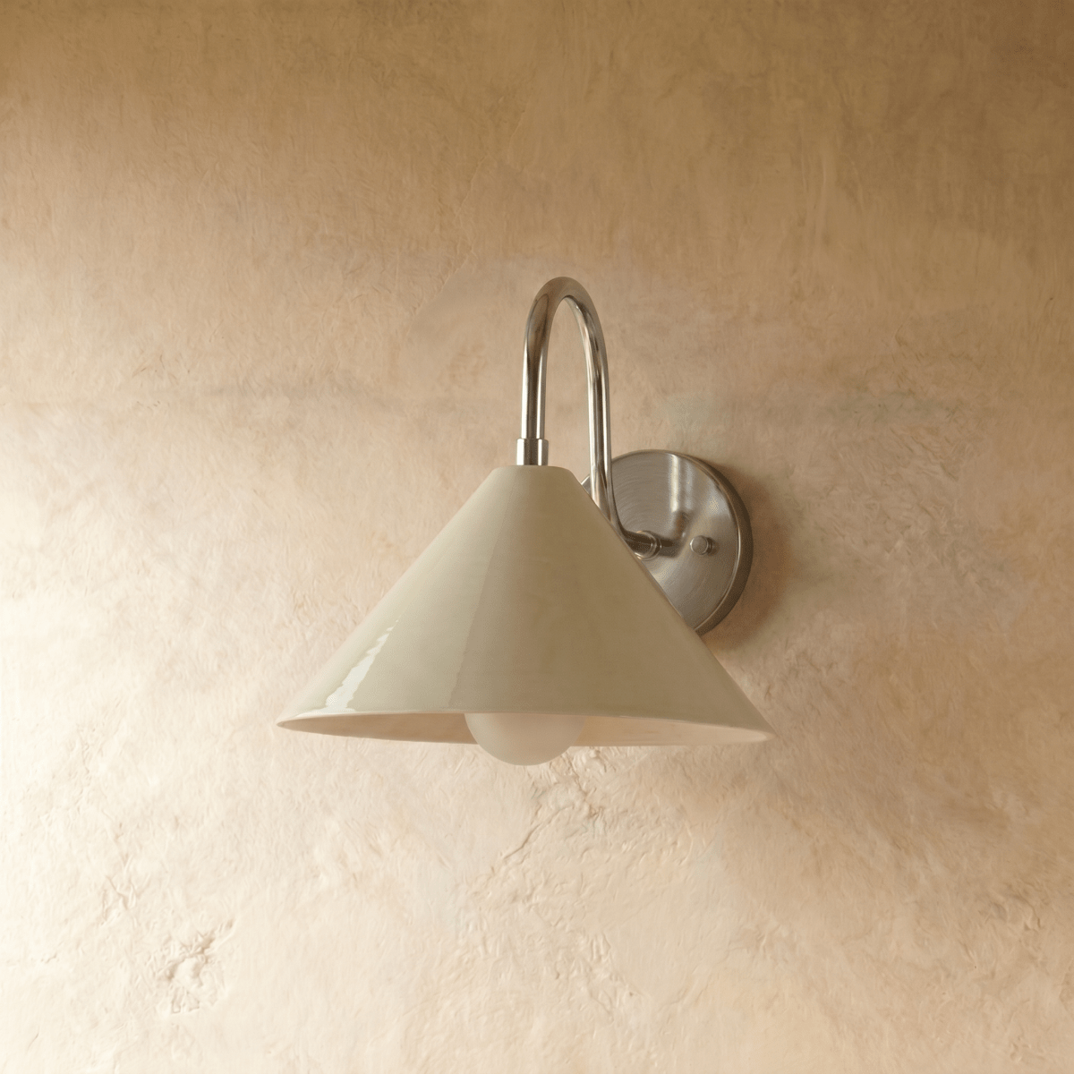 Clérachic cone-shade wall sconce in chrome, shown closer-cropped against a plain plaster studio wall.
