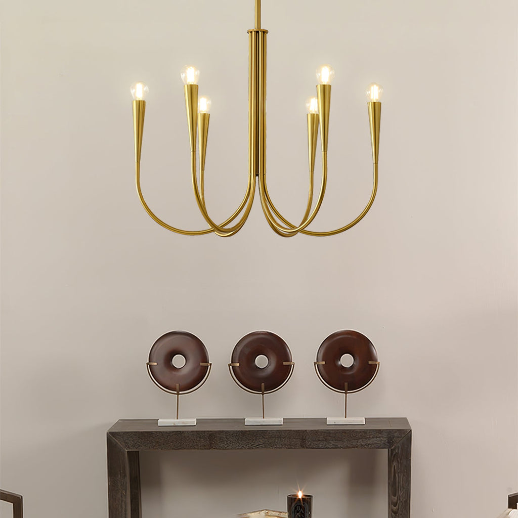 A Clérachic chandelier with brass-toned arms and conical sockets above a dark console table with three round wooden ornaments.
