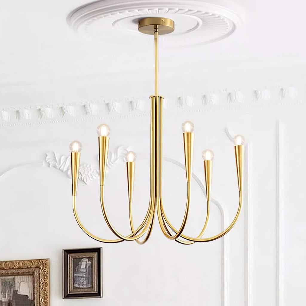 Looking up at a Clérachic chandelier in a brass tone, with a plaster ceiling rose, white wall moulding and framed pictures below.