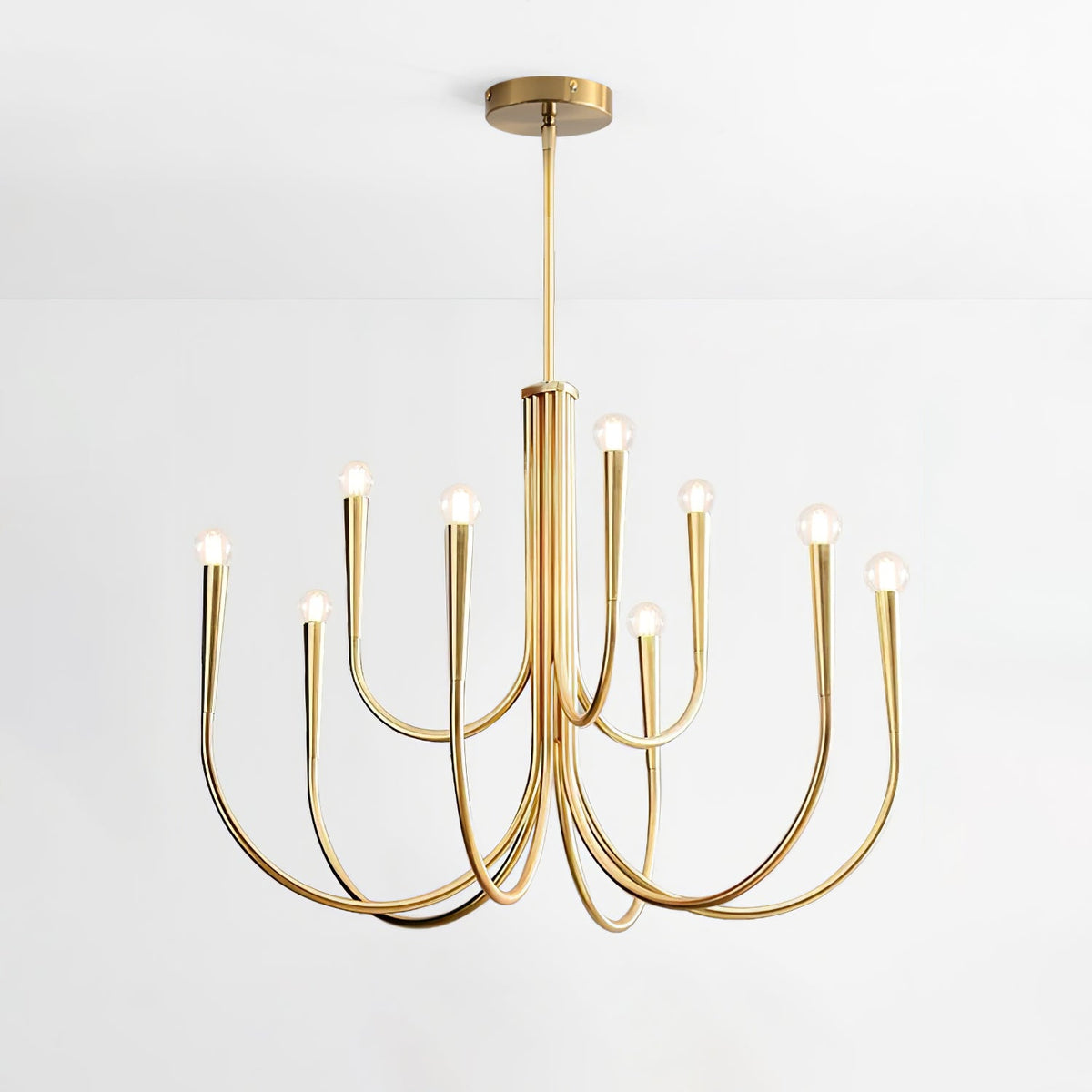 Brass-toned Clérachic chandelier with two tiers of curving arms, on a pale grey backdrop with a round ceiling plate.
