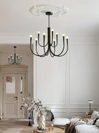 Black Clérachic chandelier under a plaster ceiling rose in a white room, with a sofa and a vase in the room behind.