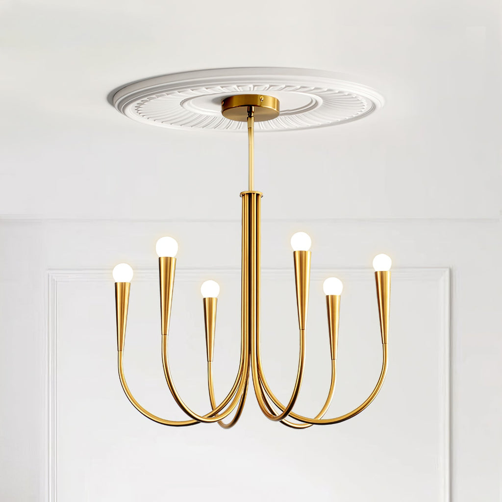 A brass-toned Clérachic chandelier with a white ceiling rose above it, against a white panelled wall.