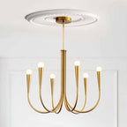 Brass-toned Clérachic chandelier with conical sockets under a plaster ceiling rose, on a white panelled wall.