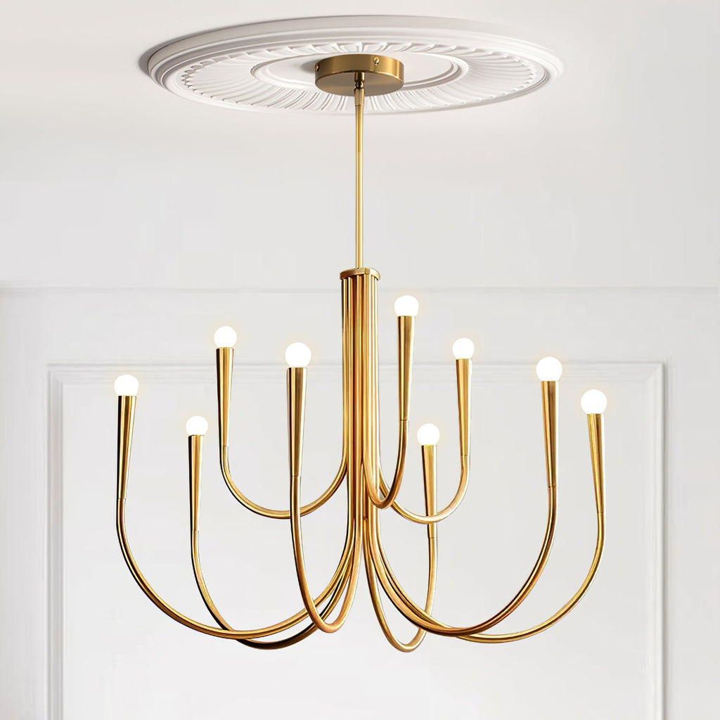 Brass-toned Clérachic chandelier under a decorative ceiling rose, with two tiers of arms against a white panelled wall.