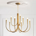 Brass-toned Clérachic chandelier under a decorative ceiling rose, with two tiers of arms against a white panelled wall.