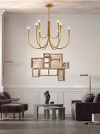 A brass-toned Clérachic chandelier in a living room with a purple sofa, a gold-framed wall piece and a pair of floor lamps.
