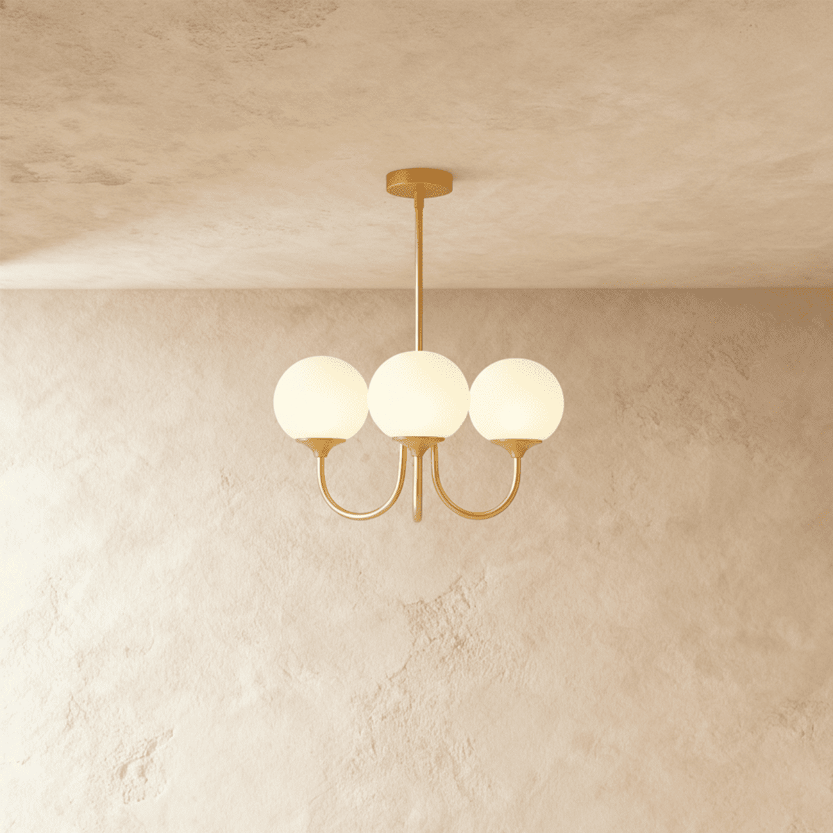 Clérachic three-light chandelier with white glass globes on curved brass-toned arms, hung from a rod against a limewash wall.