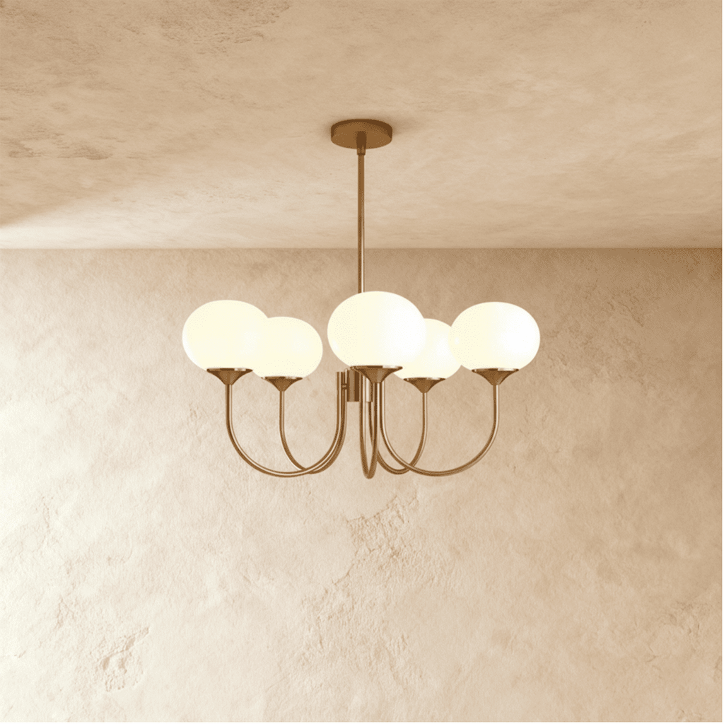 Clérachic five-light chandelier with oval white glass shades on sweeping curved arms in a soft bronze tone, lit on a limewash wall.