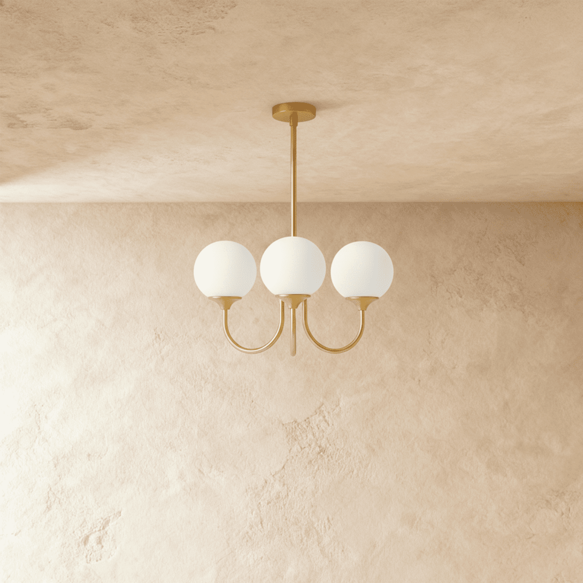Clérachic three-light chandelier with unlit white glass globes on curved brass-toned arms, shown against a limewash wall.