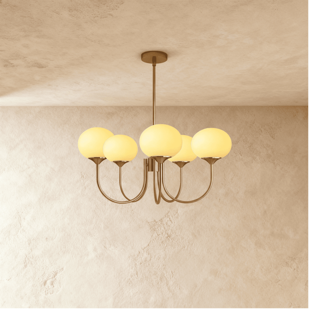 Clérachic five-light chandelier with oval cream-yellow glass shades lit warm on curved bronze-toned arms and a ceiling rod.