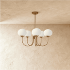 Clérachic five-light chandelier with unlit white oval glass shades on sweeping curved bronze-toned arms and a ceiling rod.