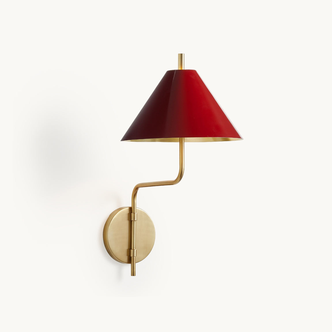 Clérachic wall light with a red metal conical shade, a curved gold arm and a round gold backplate, shown on a plain white backdrop.