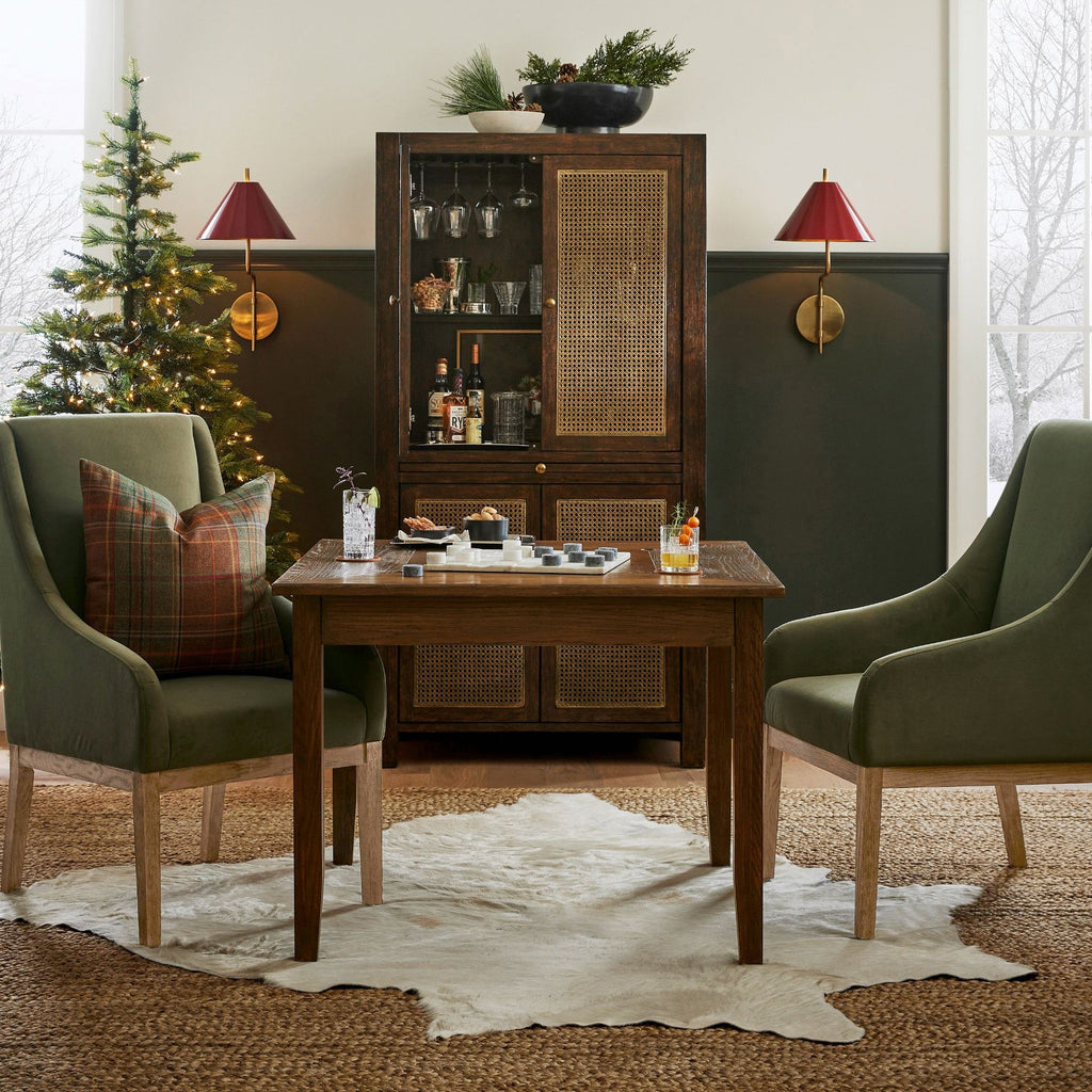 Two red-shaded Clérachic wall lights above a glazed cabinet, with green armchairs, a small table and a Christmas tree beside them.