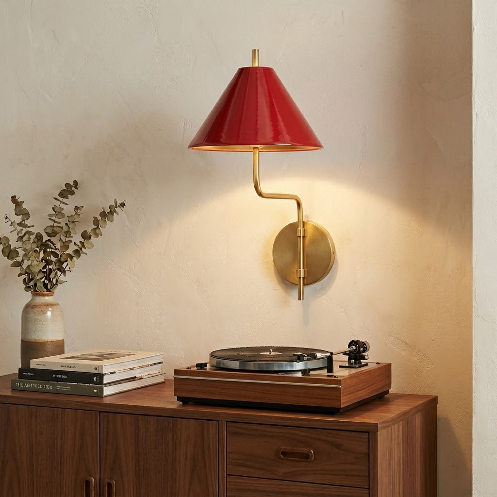 Red-shaded Clérachic wall light on a warm cream wall above a wooden cabinet holding a record player, magazines and a vase of eucalyptus.