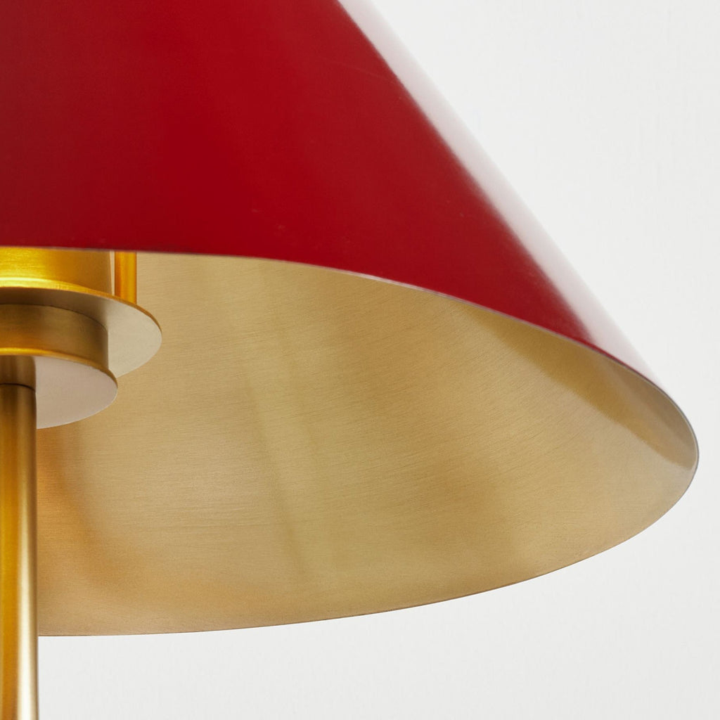 Close view of the large red conical shade of this Clérachic wall light, its brushed gold inside reflecting the light.