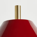 Close view of the top of the red enamel shade on this Clérachic wall light, with a brushed gold cylinder rising from the centre.