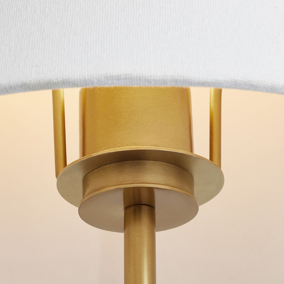 Close view of the white fabric shade and gold fitting where the arm meets the lamp holder on this Clérachic wall light.