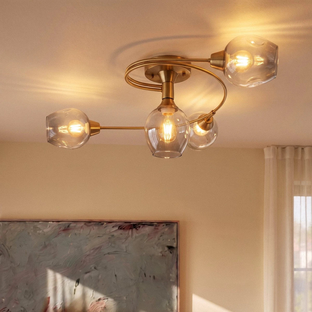 Clérachic gold ceiling light seen from below, four dimpled glass shades with filament bulbs on sweeping gold arms.