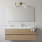 A double Clérachic wall light with brass arms and two white cone shades hangs above a white basin and a pale oak vanity.