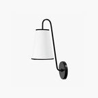 Front view of a black and white Clérachic wall light, with a black-trimmed white shade on a curved black arm.