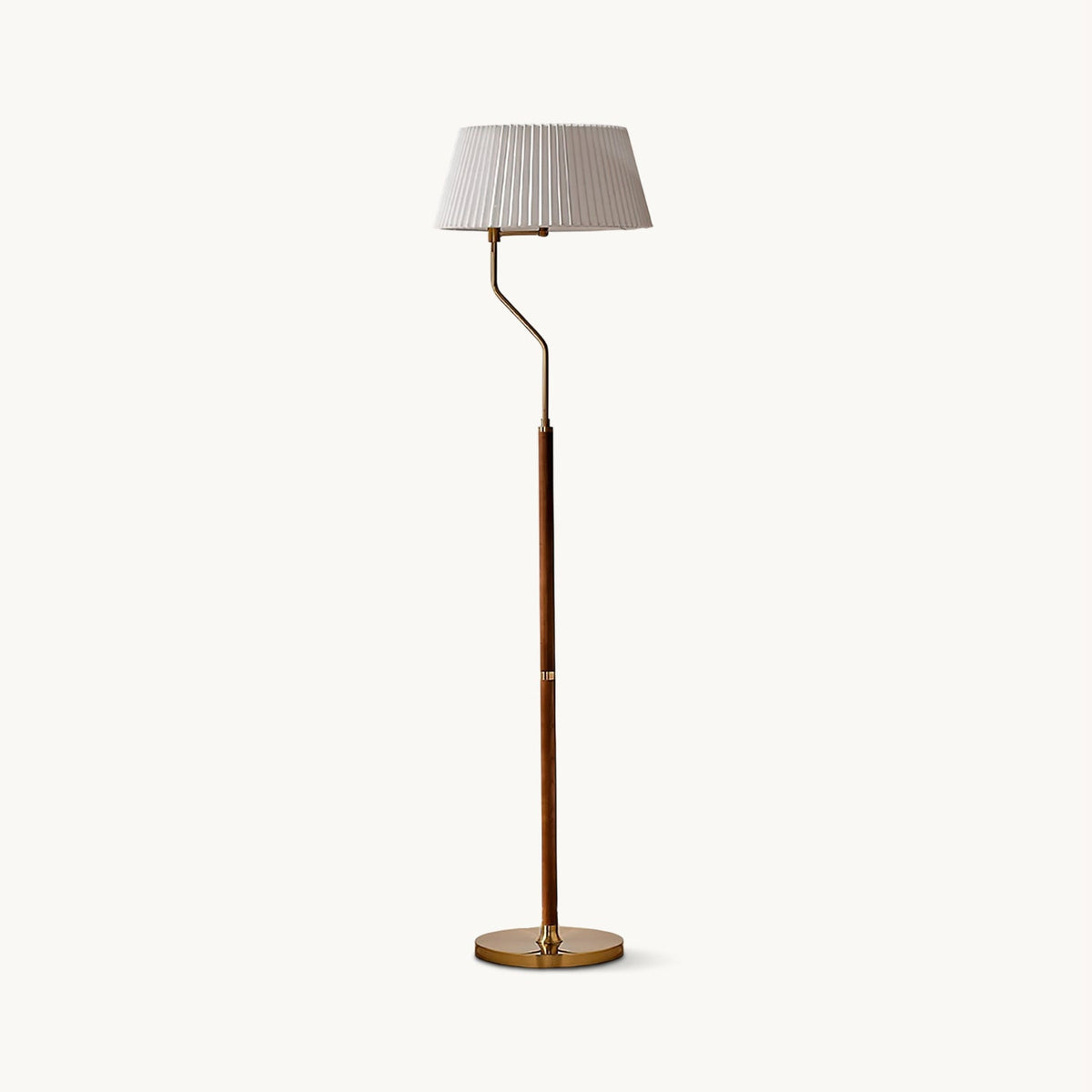 Pleated white fabric shade on a curved brass arm and walnut stem, this Clérachic floor lamp on a plain off-white backdrop.
